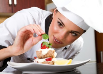 female chef decorating food in kitchen