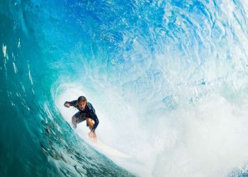 surfer on blue ocean wave in the tube getting barreled