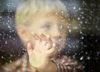 33723258 – little boy behind the window in the rain – selective focus