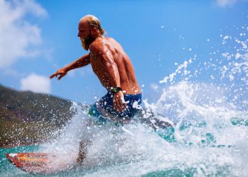 man with beard surfing wave splash actively