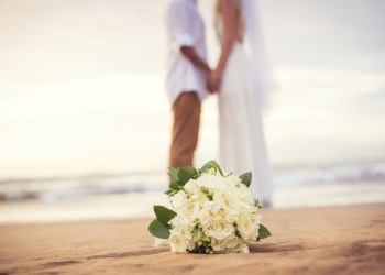 Just married couple holding hands on the beach