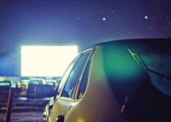 A parked car at a drive-in movie theater