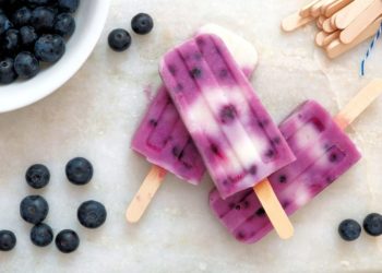 40300500 - blueberry vanilla popsicles in a cluster with fresh berries on a white marble background