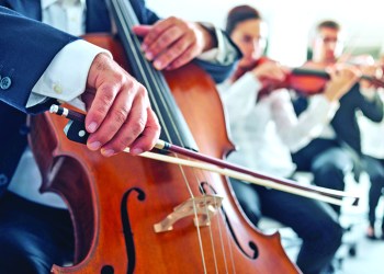 46506738 - professional cello player's hands close up, he is performing with string section of the symphony orchestra