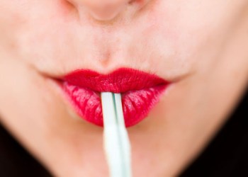 Woman wearing red lipstick using a straw