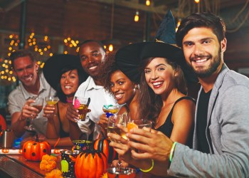 Friends enjoying a Halloween party at a bar look to camera