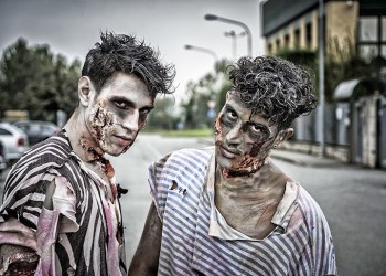 Two male zombies standing in empty city street looking at camera