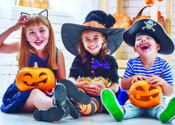 62765546 - happy brother and two sisters on halloween. funny kids in carnival costumes indoors. cheerful children play with pumpkins and candy.