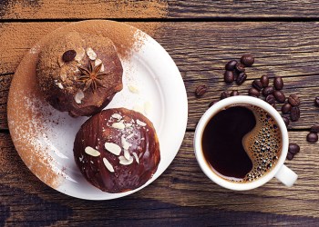 top view of a cup of coffee and cupcake with chocolate and nuts on wooden table