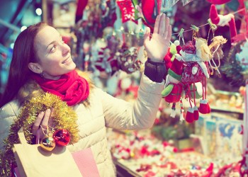 Cheerful girl customer near counter with Christmas gifts in evening time selects gifts for loved ones