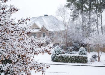 Snow covered home, street and yards