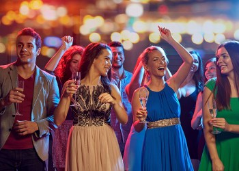 party, holidays, celebration, nightlife and people concept - happy friends with glasses of non-alcoholic champagne dancing at disco in nightclub