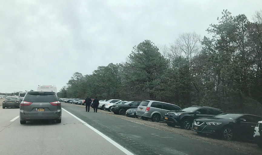 Police officers walk past all the cars parked for funeral of fallen NYPD Detective Brian Simonsen on Montauk Highway in Hampton Bays