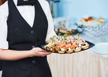 waitress catering service. female staff servicing dish full of snack food at restaurant event