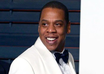 Jay-Z smiling while wearing a white tuxedo with black tie in 2015