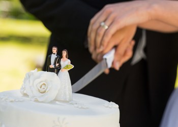 Extreme close-up mid section of a newlywed cutting wedding cake