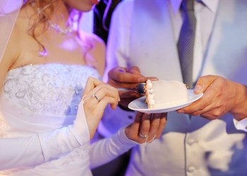 a bride and a groom are eating their wedding cake