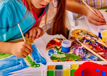 Close up of girl with brush painting in kindergarten .