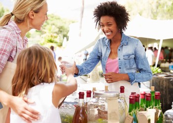 Woman Selling Soft Drinks At Farmers Market Stall