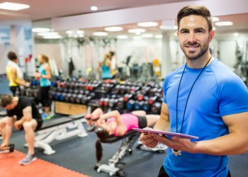 Handsome trainer using tablet in weights room at the gym