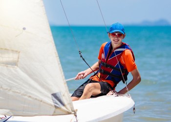 Young man sailing. Teenager boy on sea yacht. Healthy water sport. Yachting class for teen age sailor. Ocean vacation on boat. Regatta on tropical island. Beach and sail activity.