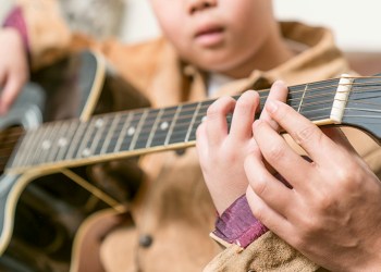 teacher giving guitar lessons to pupil in a classroom