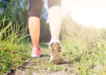 Walking or running exercise, legs on green grass footpath in forest, achievement fitness adventure and exercising in spring or summer nature