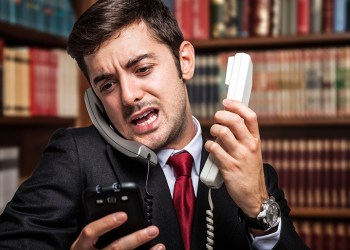 Stressed businessman talking on many phones at once