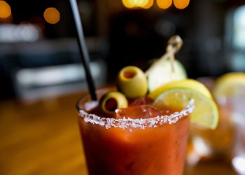 Cold bloody mary cocktail garnished with lemon, lime, green olive and salt