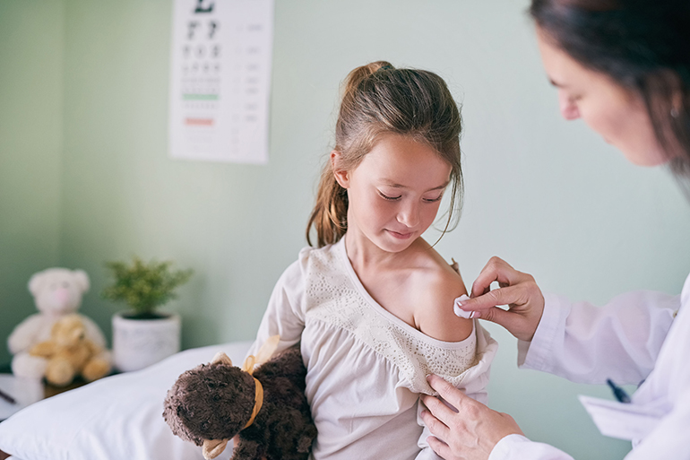 Shot of a pediatrician cleaning her young patients arm with a cotton ball