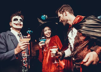 Young People Drinking Cocktails at Halloween Party. Group of Young Smiling Friends Wearing Halloween Costumes Drinking Cocktails and having Fun in Nightclub. Celebration of Halloween