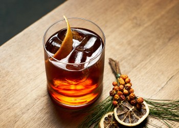 Alcohol whiskey cocktail or cognac with cola citrus and ice cubes on wooden table background