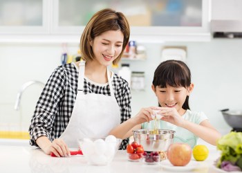 Happy mother and child in kitchen preparing cookies