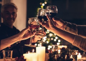 Close up shot of family toasting wine at christmas dinner. Family enjoying christmas dinner together at home, with focus on hands and wine glasses.