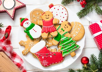 Christmas gingerbread in the plate, red present box and decorations on white wooden background. Christmas baking. Top view.