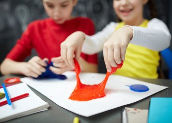 Human hands pulling red slime during play