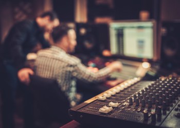 Sound engineer and producer working together at mixing panel in the boutique recording studio.