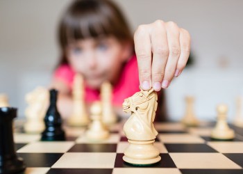 Young white child playing a game of chess on large chess board.