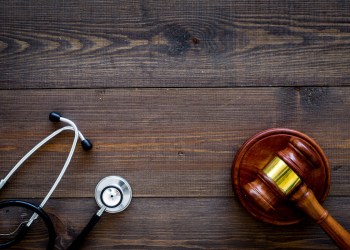 Medical law, health law concept. Gavel and stethoscope on dark wooden backgound top view copy space