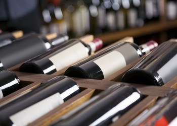 Red wine bottles displayed on shelves in supermarket