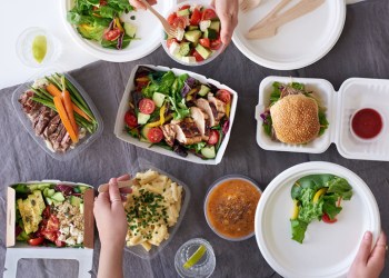 Convenient takeaway takeout food for party, overhead spread of assorted food with hands serving up