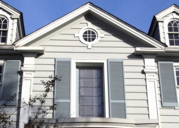 Photo of the upper half of a light green colonial style home.