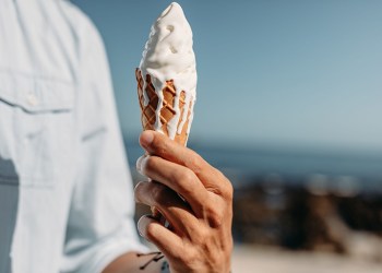 Close up of hand of man holding a melting ice cream cone. Man holding an ice cream on sunny day.