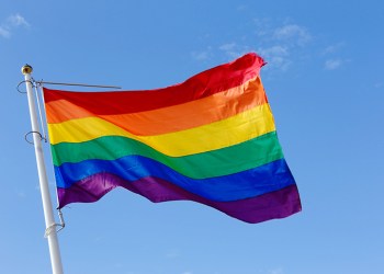 Close-up of a rainbow flag on blue sky.