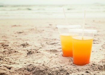 Orange juice in a glass on the beach. Summer concept.