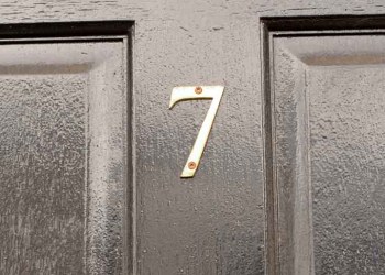 House number 7 sign on black door with brass door knocker