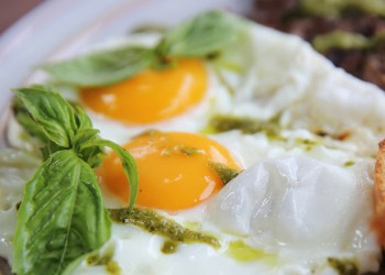 Grilled beef steak with toast , fried egg and vegetables on top with pesto sauce