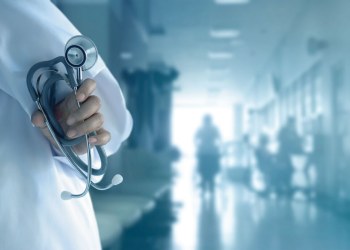 Doctor with stethoscope in hand on hospital background