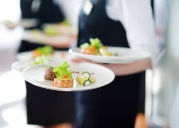 Waiter carrying plates with meat dish