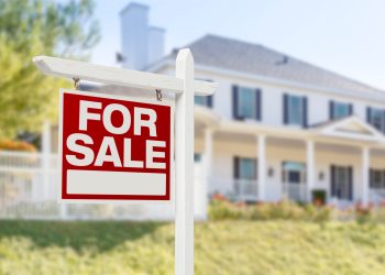 Home For Sale Real Estate Sign in Front of Beautiful New House.